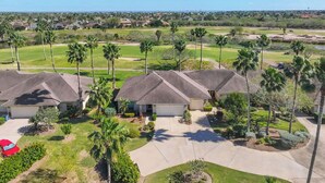 Zona residencial con casas, palmeras y un campo de golf al fondo.