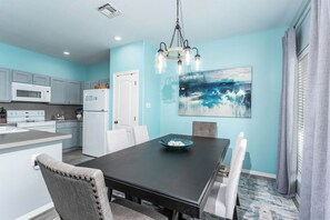 A modern kitchen with white appliances, a dining table with chairs, and a large abstract painting on the wall. - Bonita Vista Villa  -27 GH (Laguna Vista)