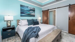 Un dormitorio con cama, mesitas de noche, cómoda, un cuadro grande y una puerta corrediza de estilo granero.