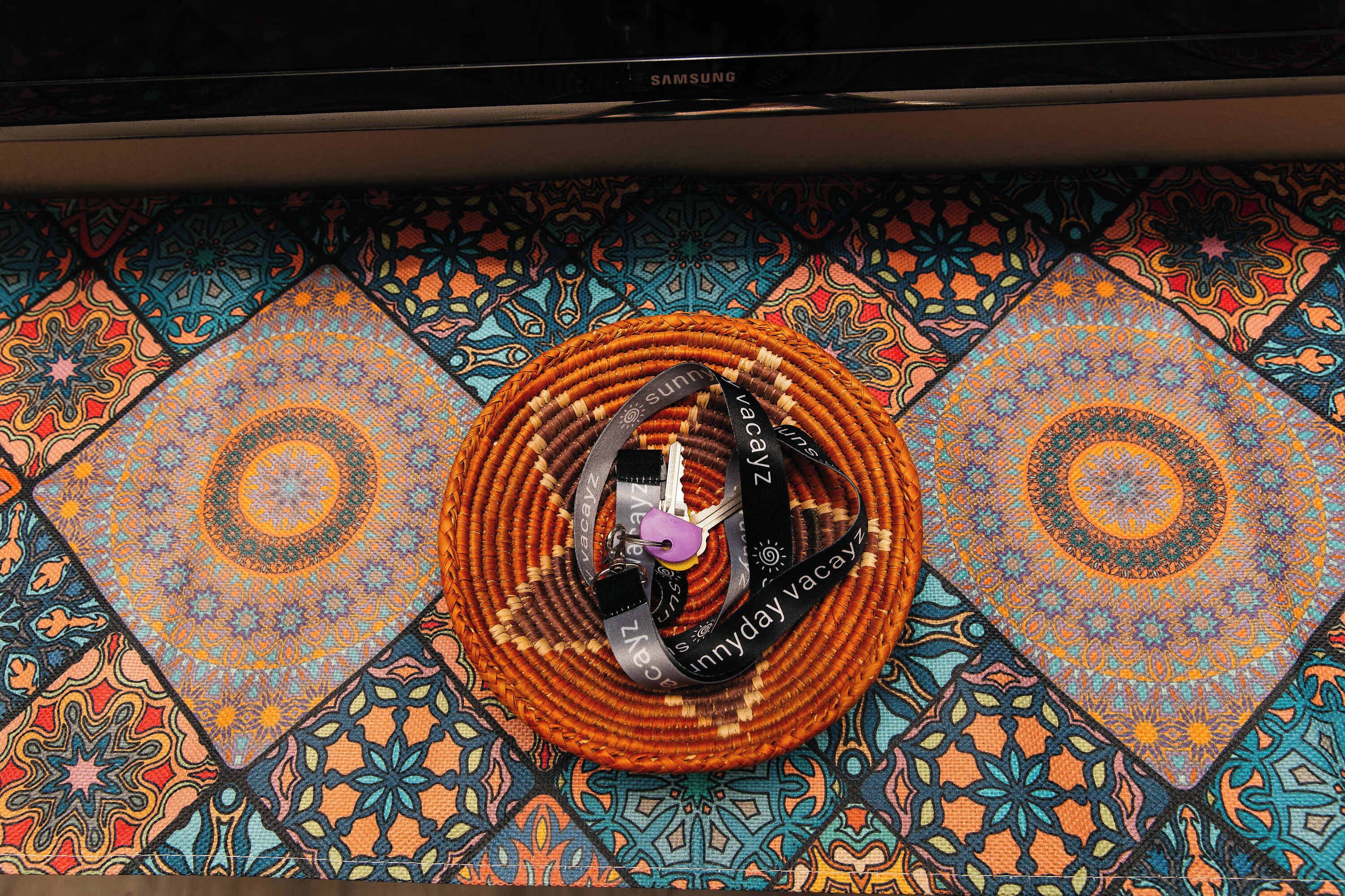 A woven basket with a strap and buckle on a patterned floor.