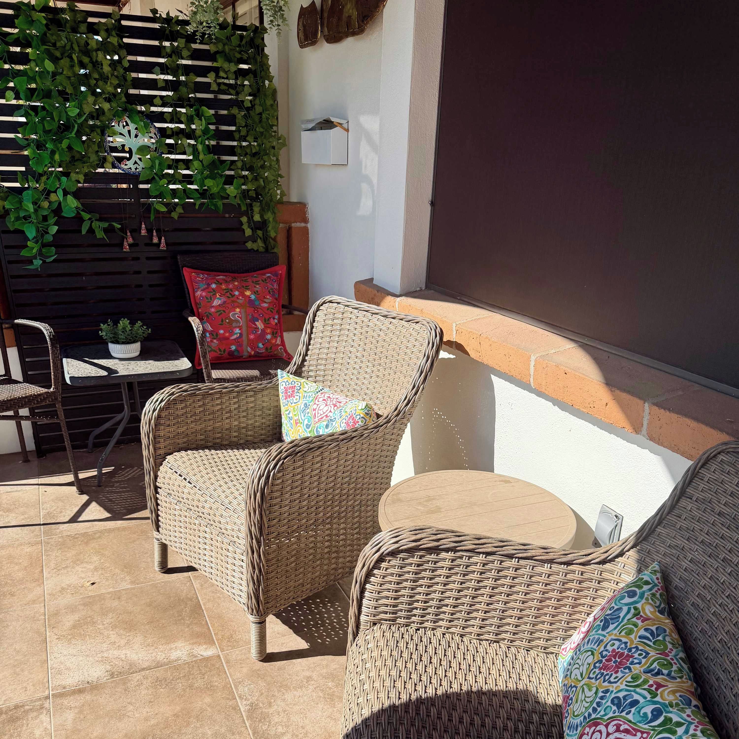 A patio area with wicker furniture, a small table, and a potted plant.