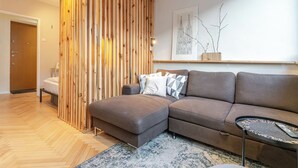 Ein modernes Wohnzimmer mit einer Holzwand, einem grauen Sofa und einem kleinen Tisch.