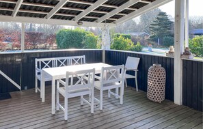 A covered outdoor seating area with a table and chairs, a lantern, and a decorative vase. - 3 bedroom awesome home in Melby (Melby)