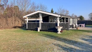 A small, single-story building with a covered porch and a fenced yard.