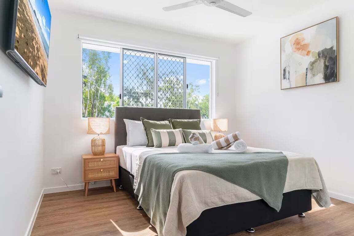 A bedroom with a bed, bedside tables, a window, and artwork on the walls.