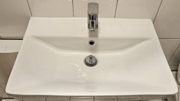 A white bathroom sink with a chrome faucet and a single drain.
