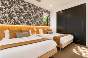 Une chambre d’hôtel avec deux lits, une grande fenêtre et une porte sombre.