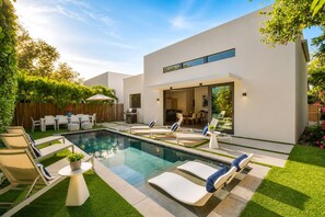 A modern outdoor pool area with lounge chairs and a dining area.