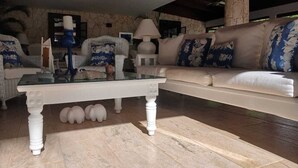 A living room with a glass coffee table, white sofas, and a patterned rug.