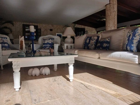 Una sala de estar con una mesa de centro de vidrio, sofás blancos y una alfombra estampada.