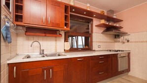 Una cocina con armarios de madera, un lavamanos de acero inoxidable, una ventana y un horno empotrado.