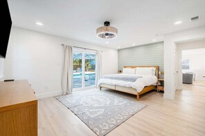 A bedroom with a bed, a desk, a large window, and a view of a pool. - Backyard Oasis, Pool,Sandy Magnolia, Sleeps 16,Eastern Lake,Golf Cart, Bikes (Santa Rosa Beach)
