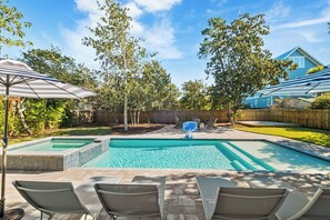 A backyard with a rectangular swimming pool, surrounded by lounge chairs and a wooden fence. - Backyard Oasis, Pool,Sandy Magnolia, Sleeps 16,Eastern Lake,Golf Cart, Bikes (Santa Rosa Beach)