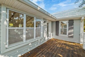 A covered porch with large windows and a wooden deck. - Backyard Oasis, Pool,Sandy Magnolia, Sleeps 16,Eastern Lake,Golf Cart, Bikes (Santa Rosa Beach)
