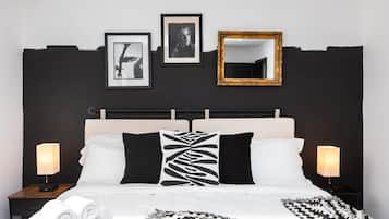 Une chambre à coucher avec un lit, deux tables de chevet, un miroir et trois tableaux encadrés accrochés au mur.