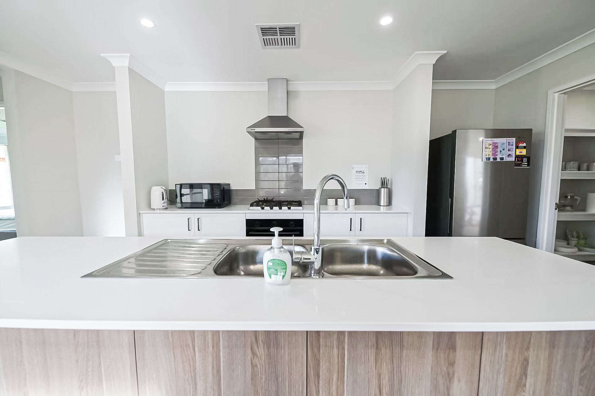 Een moderne keuken met een centraal eiland, roestvrijstalen apparatuur en een inbouwoven.