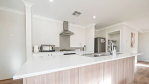 Cocina moderna con isla central, muebles blancos, electrodomésticos de acero inoxidable y un amplio ventanal que proporciona luz natural.