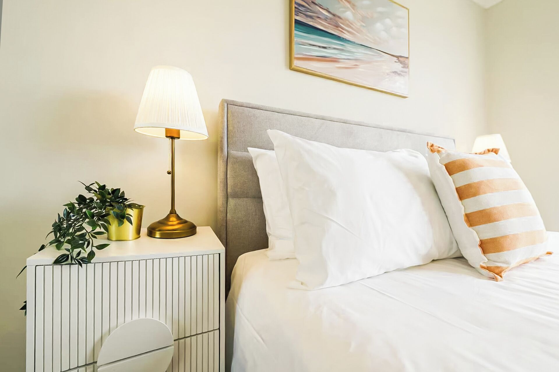 Une chambre à coucher bien rangée, avec un lit, des oreillers, une table de chevet avec une lampe et un radiateur.