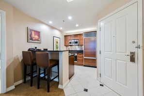 A compact kitchen with a central island, wooden cabinets, and a microwave. - SVS: 2BD/3BA Suite | SPHERE & Mountain Views | Balcony | Signature at MGM (Las Vegas)