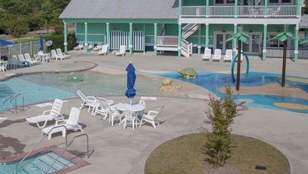 Un complexe hôtelier doté d’une piscine, de chaises longues et d’un bâtiment avec un balcon.