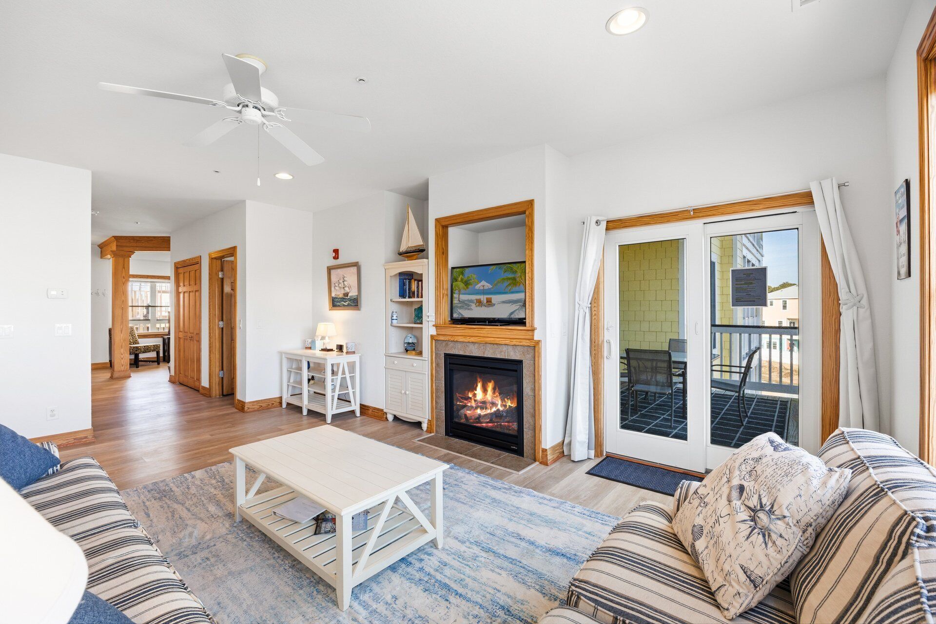 A spacious living room with a fireplace, a television, and a balcony with a view.