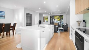 Una cocina moderna con una isla central, suelo de madera y un comedor con sillas.