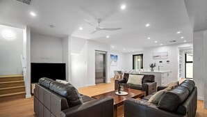 Ein modernes Wohnzimmer mit Ledersofas, einem Holztisch und einem Deckenventilator.