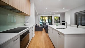 Eine moderne Küche mit weißen Schränken, einer zentralen Kochinsel und einem Essbereich mit einer Couch und einem Tisch.