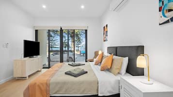 A modern bedroom with a bed, bedside table, TV, and a view of the outdoors.