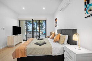 Een moderne slaapkamer met een bed, nachtkastje, televisie en uitzicht op de omgeving.