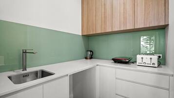 A compact kitchen with a sink, a kettle, and a toaster on the countertop.