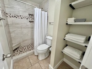 Ein Badezimmer mit Dusche, Toilette und Handtuchhaltern.