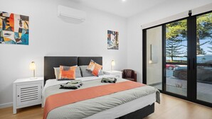 Une chambre moderne avec un grand lit, deux tables de chevet et des œuvres d’art accrochées aux murs.