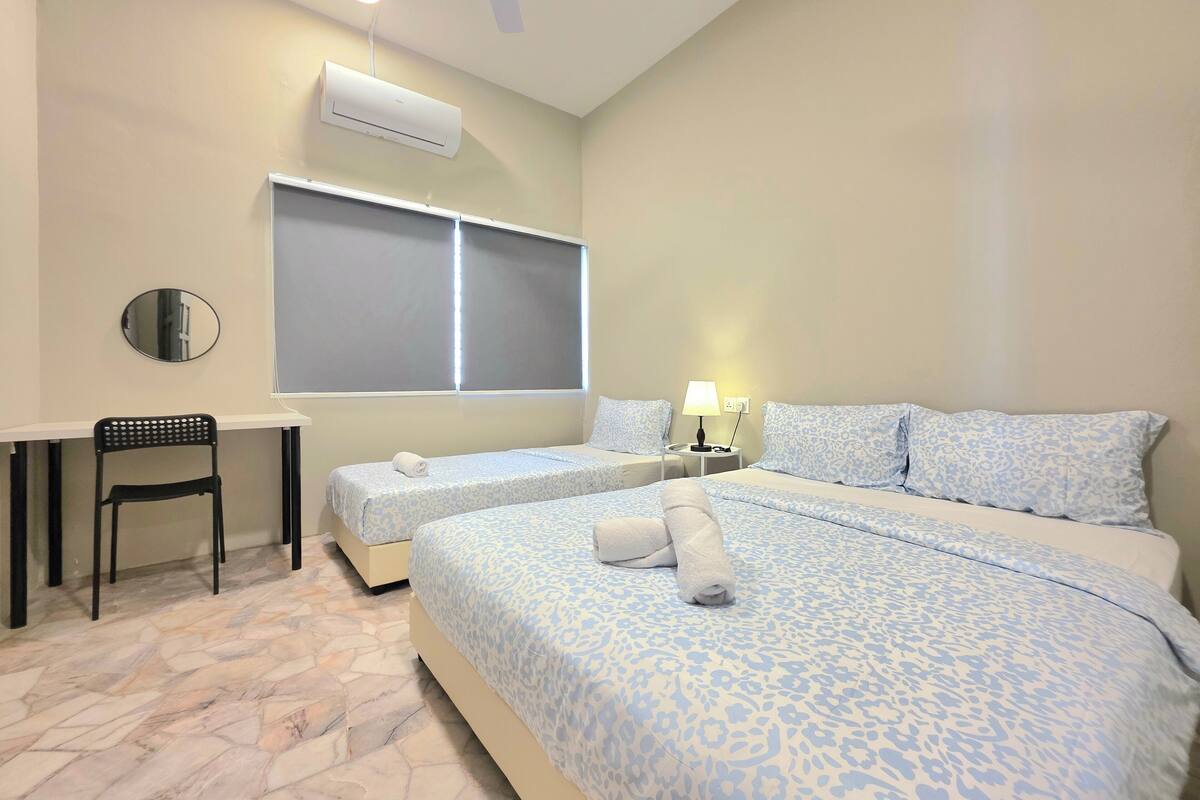 Habitación de hotel con dos camas, un escritorio, una silla y un equipo de aire acondicionado.