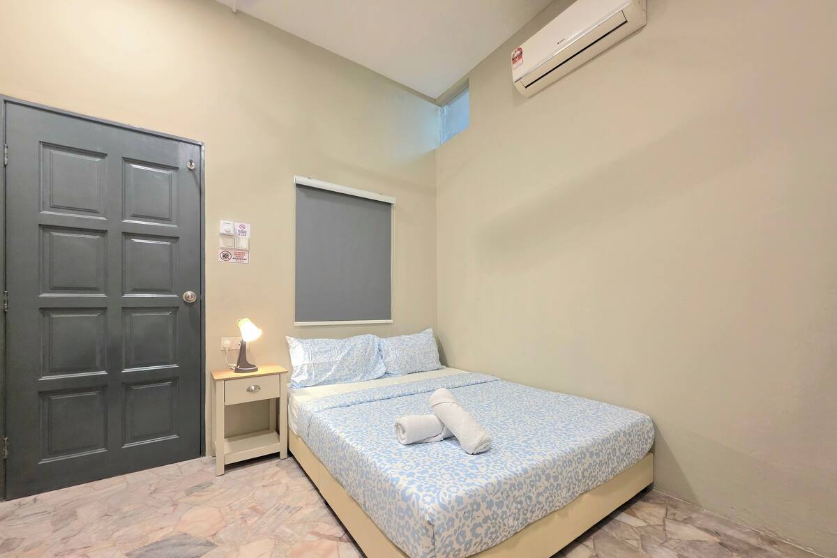 Un dormitorio con cama, mesita de noche, aire acondicionado de pared y una puerta.