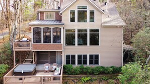 Een huis met twee verdiepingen, een terras, een overdekte veranda en een groot raam.