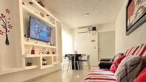 A living room with a TV, white walls, a dining area, and a sofa. - Diamond zone apartment with pool (Acapulco de Juárez)