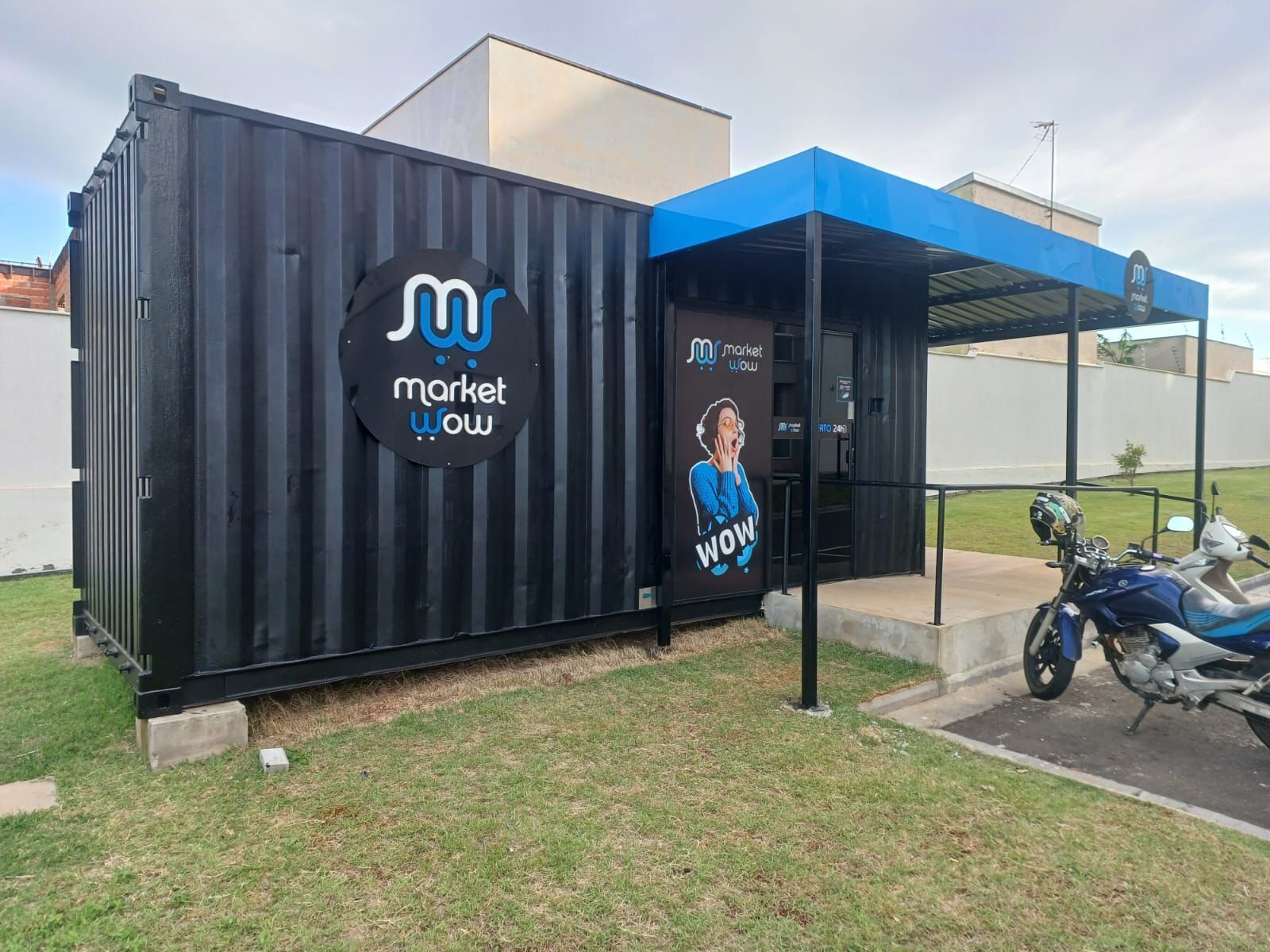 Une structure métallique noire surmontée d’une marquise bleue, portant l’inscription « Market Wow » et illustrée d’une image de femme.