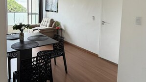 Una sala de estar moderna con comedor, un sofá, una mesa de centro y una planta en maceta.