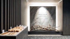 A modern interior with a marble wall and a display of wooden branches. - REGIONIA by Quintessa Sapporo Sta. Front (Sapporo)