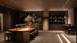 Ein modernes Interieur mit einem zentralen Esstisch, Sitzgelegenheiten und einer dekorativen Pflanzengruppe.