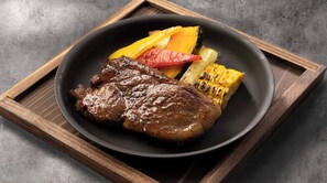 A plate with grilled steak, grilled corn, and grilled vegetables.