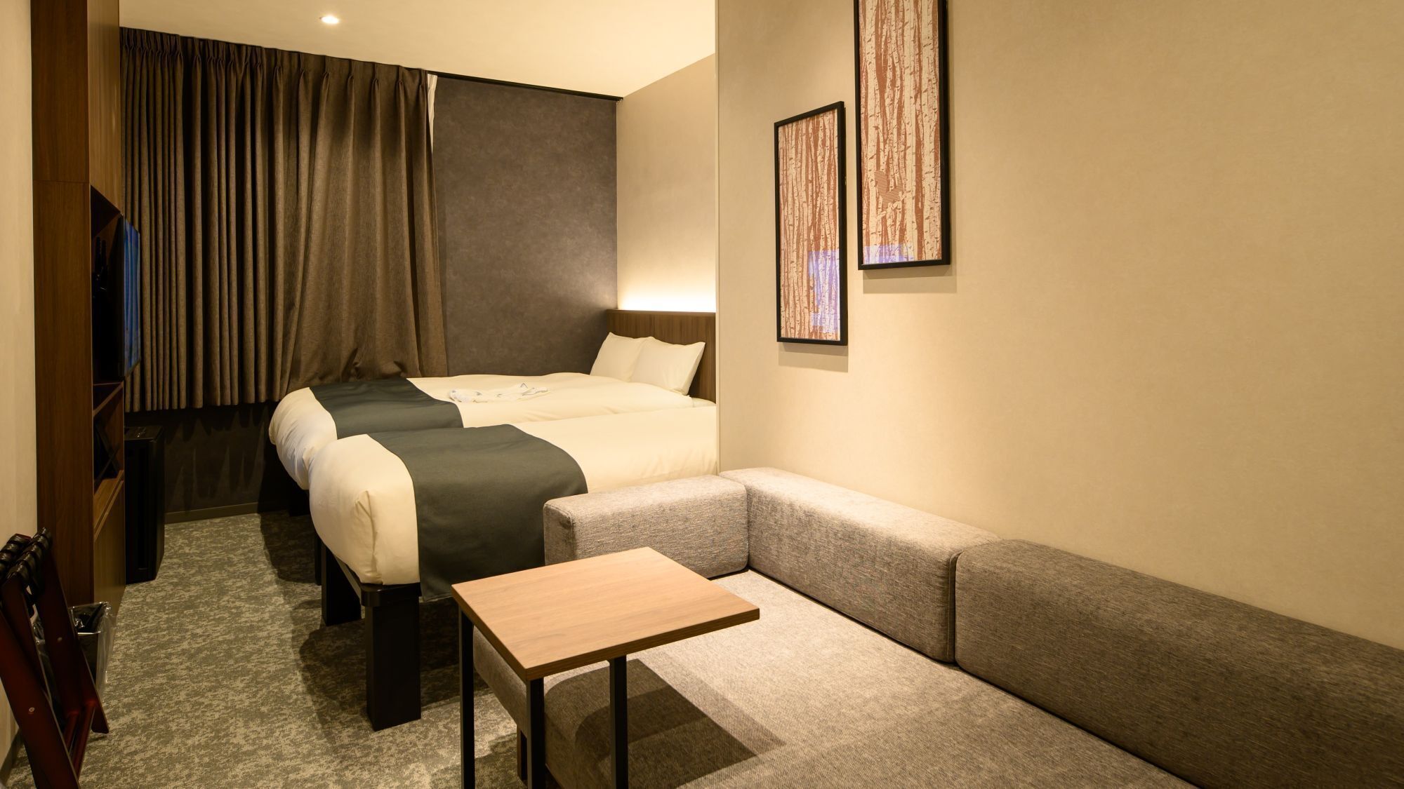 A hotel room with two beds, a sofa, a small table, and a TV.