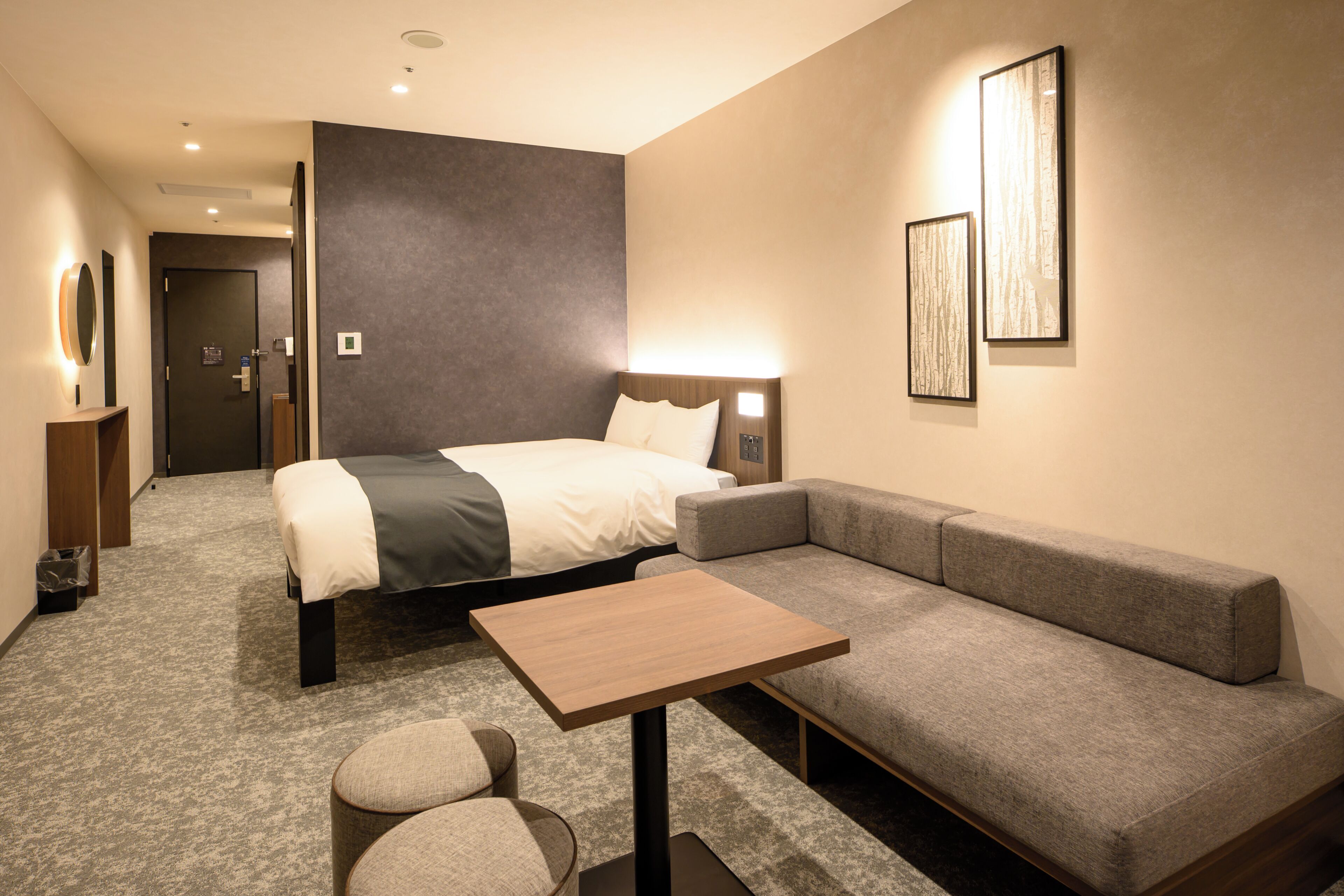 Ein Hotelzimmer mit Bett, einer Couch, einem kleinen Tisch und einem Spiegel.
