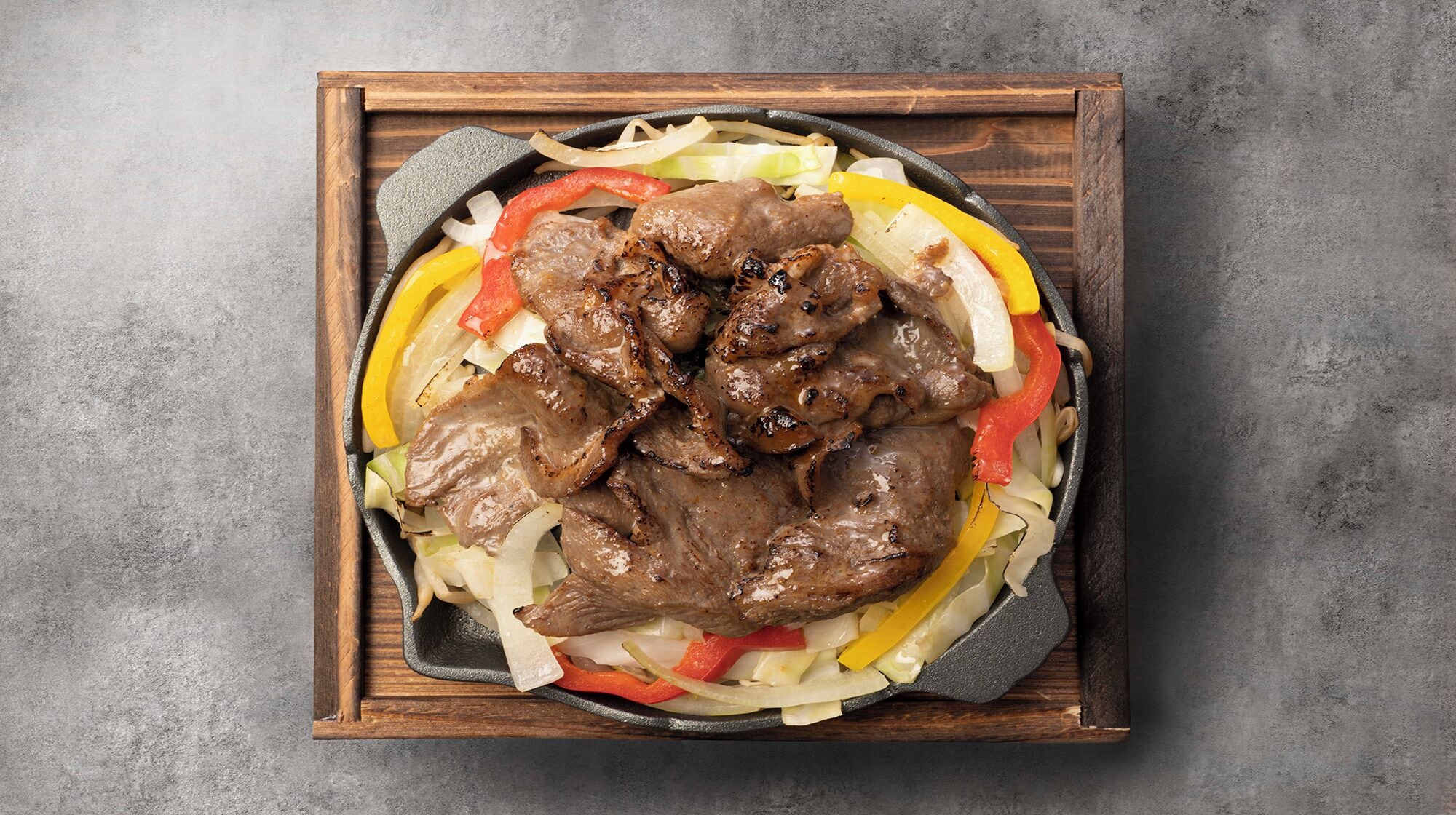 Uma frigideira com carne grelhada e legumes.