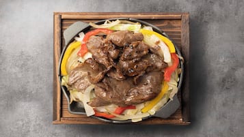 Uma frigideira com carne grelhada e legumes.