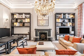 A modern living room with a fireplace, a chandelier, and a television. - Cadogan Square Ultra-luxe 4BR Private Garden (London)