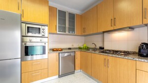 Una cocina moderna con armarios de madera, electrodomésticos de acero inoxidable y encimera de granito.