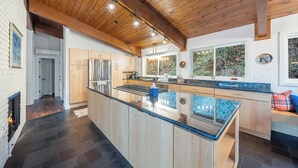 Eine moderne Küche mit einer großen Kochinsel, Holzbalken an der Decke und Blick ins Freie.