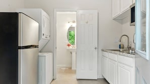 Eine Küche mit weißen Schränken, einem Kühlschrank, einer Mikrowelle und einem Spülbecken.